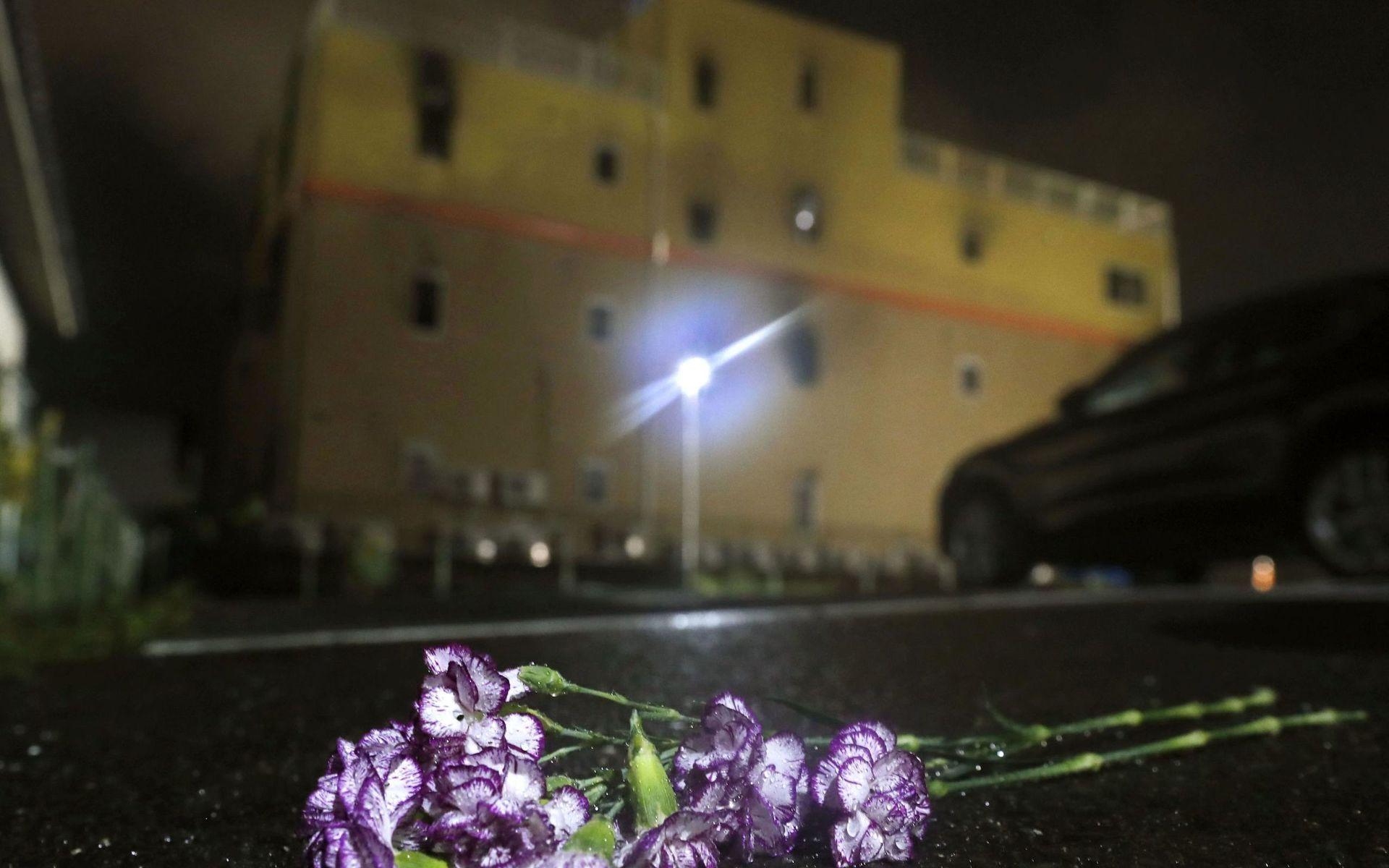 Blommor ligger framför den brandhärjade byggnaden.