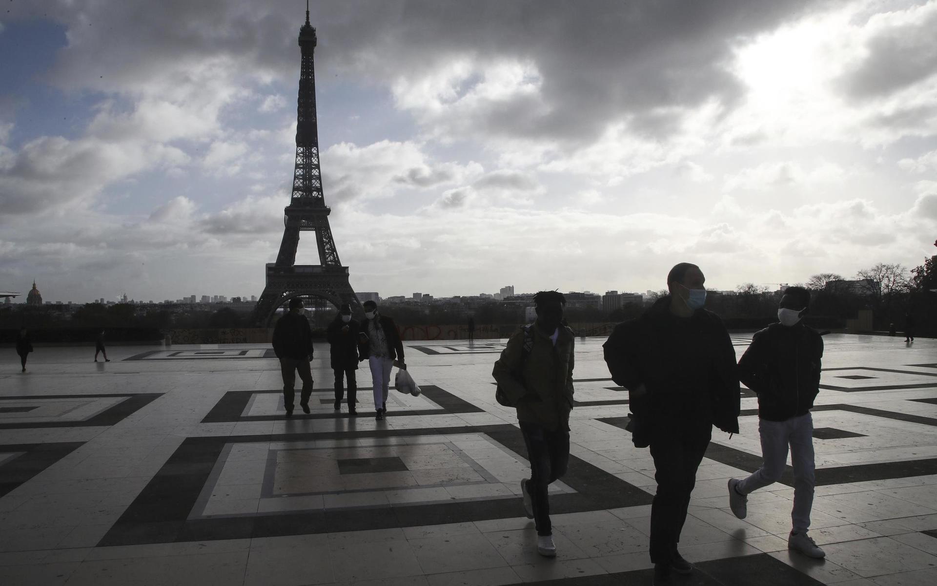 Människor med ansiktsmask går förbi Eiffeltornet i Paris. 