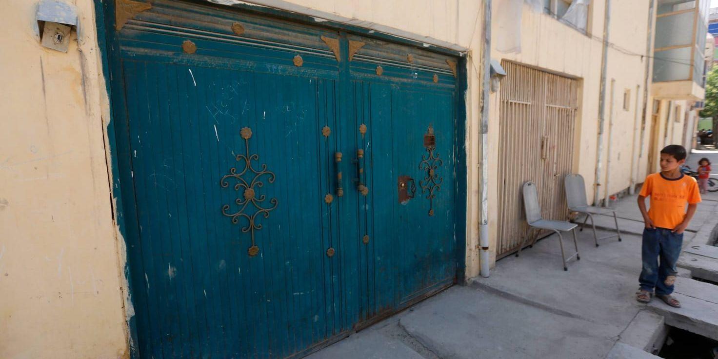 En afghansk pojke tittar på entrén till det hus i Kabul där en finländsk kvinna blev kidnappad och två andra personer dödades.
