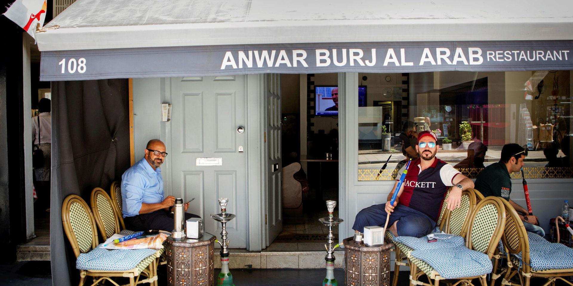 Abod Salah och Omar Kader sitter utanför restaurangen och röker. De hejar båda på England och tror att de vinner på lördag.