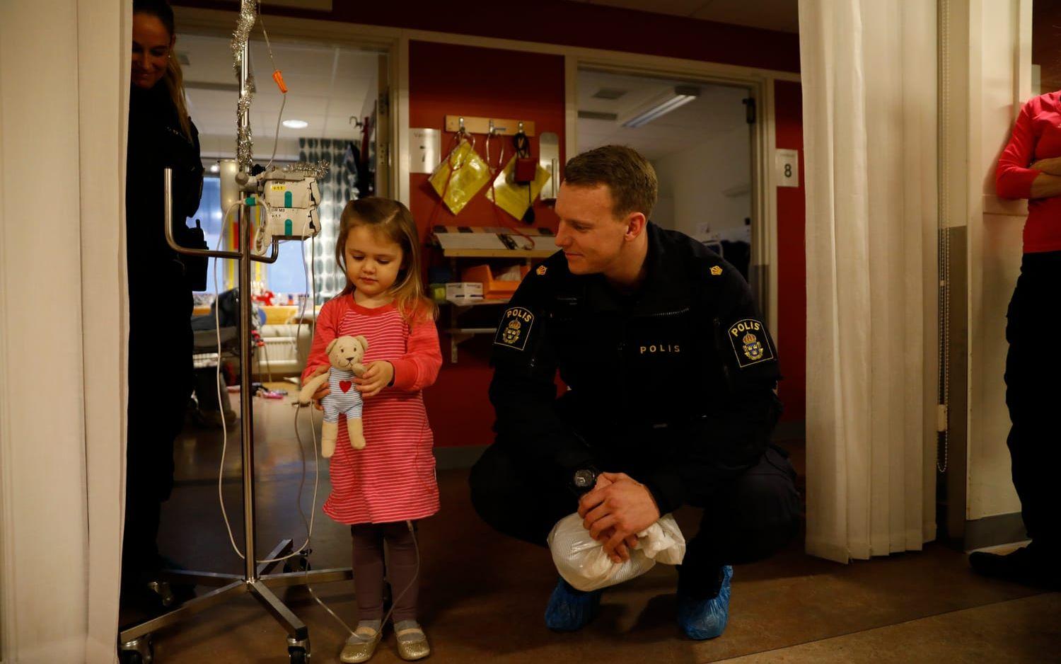 Nina, 3 år, vårdas på barncanceravdelningen på Drottning Silvias sjukhus. Här är hon klädd med sin julklänning med hjärtan på och håller i nallen som hon precis har fått från polisen Jesper.