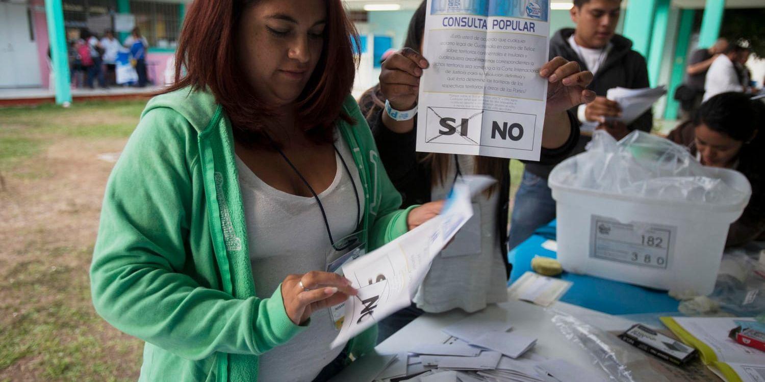 En valarbetare visar upp en röstsedel där "ja" kryssats för i söndagens folkomröstning om gränstvisten med grannlandet Belize.