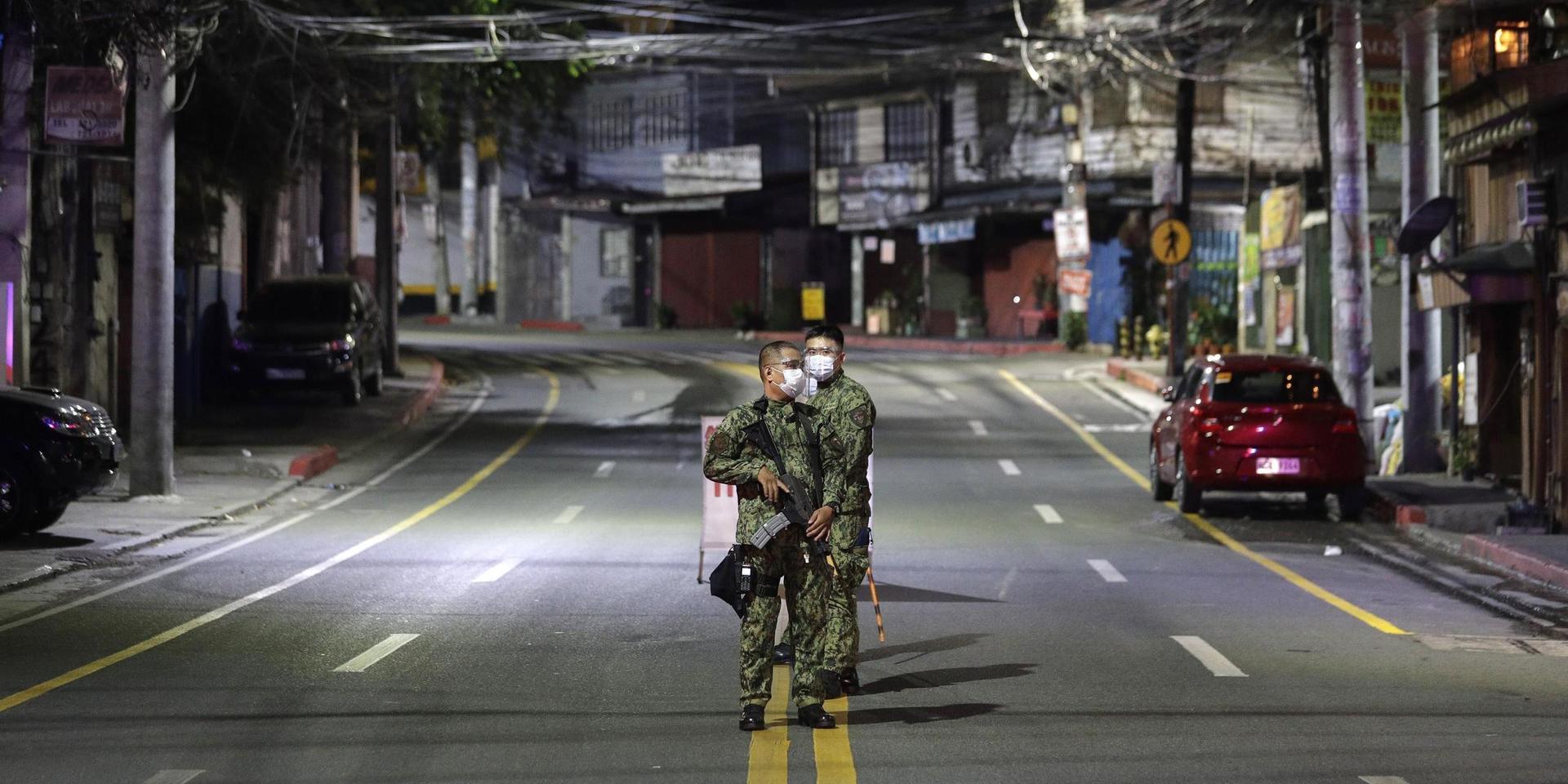 Beväpnade soldater bevakar en tom gata i Metro Manila, Filippinerna, efter att utegångsförbudet trätt i kraft.