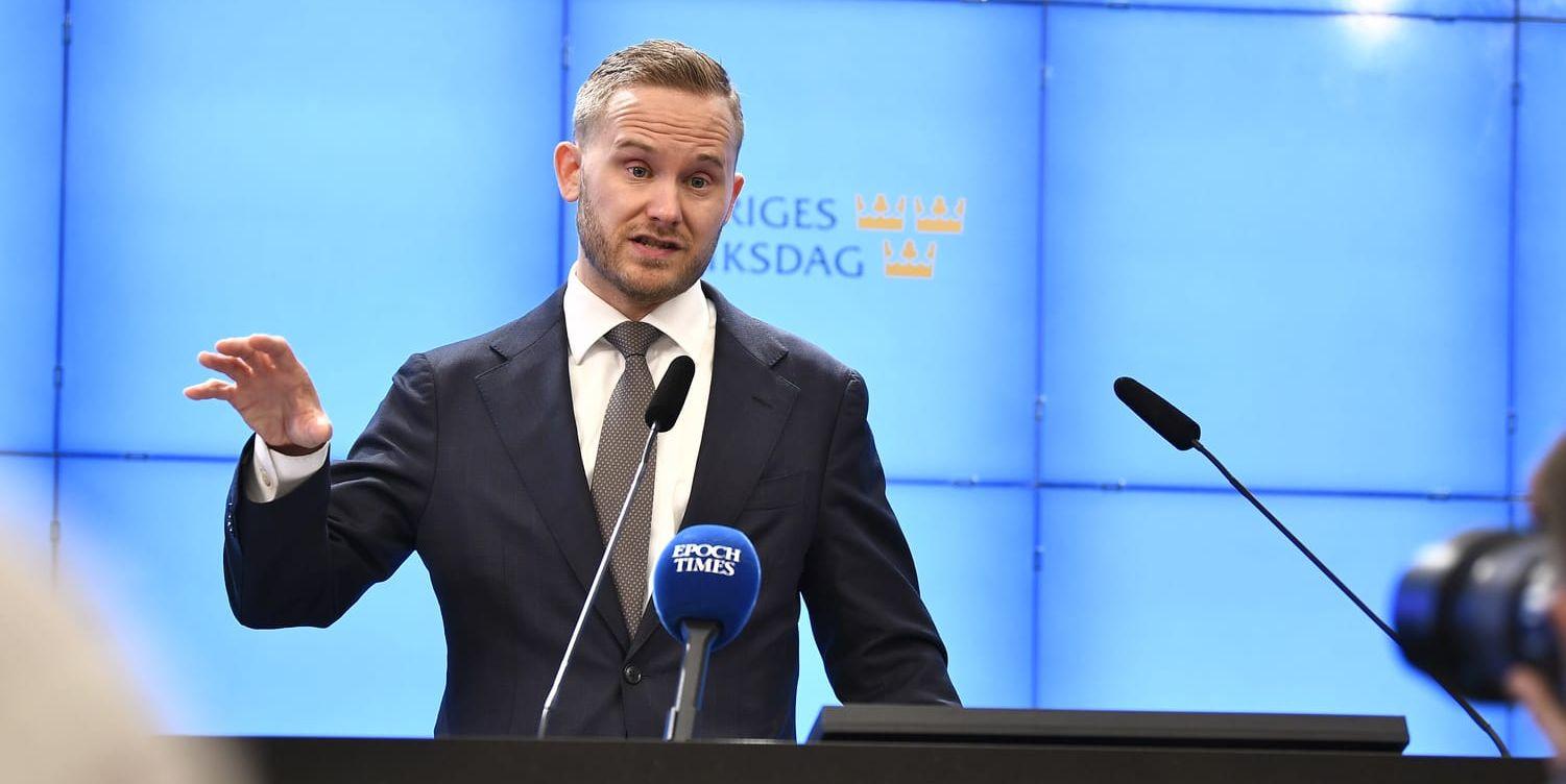 Sverigedemokraten Henrik Vinge framför mikrofoner.