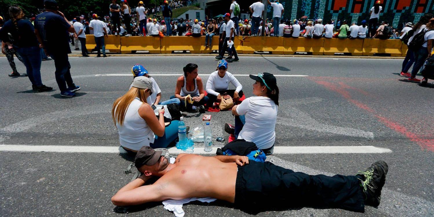 Demonstranter protesterar mot regimen i Venezuela genom sittstrejker för att lamslå trafiken.