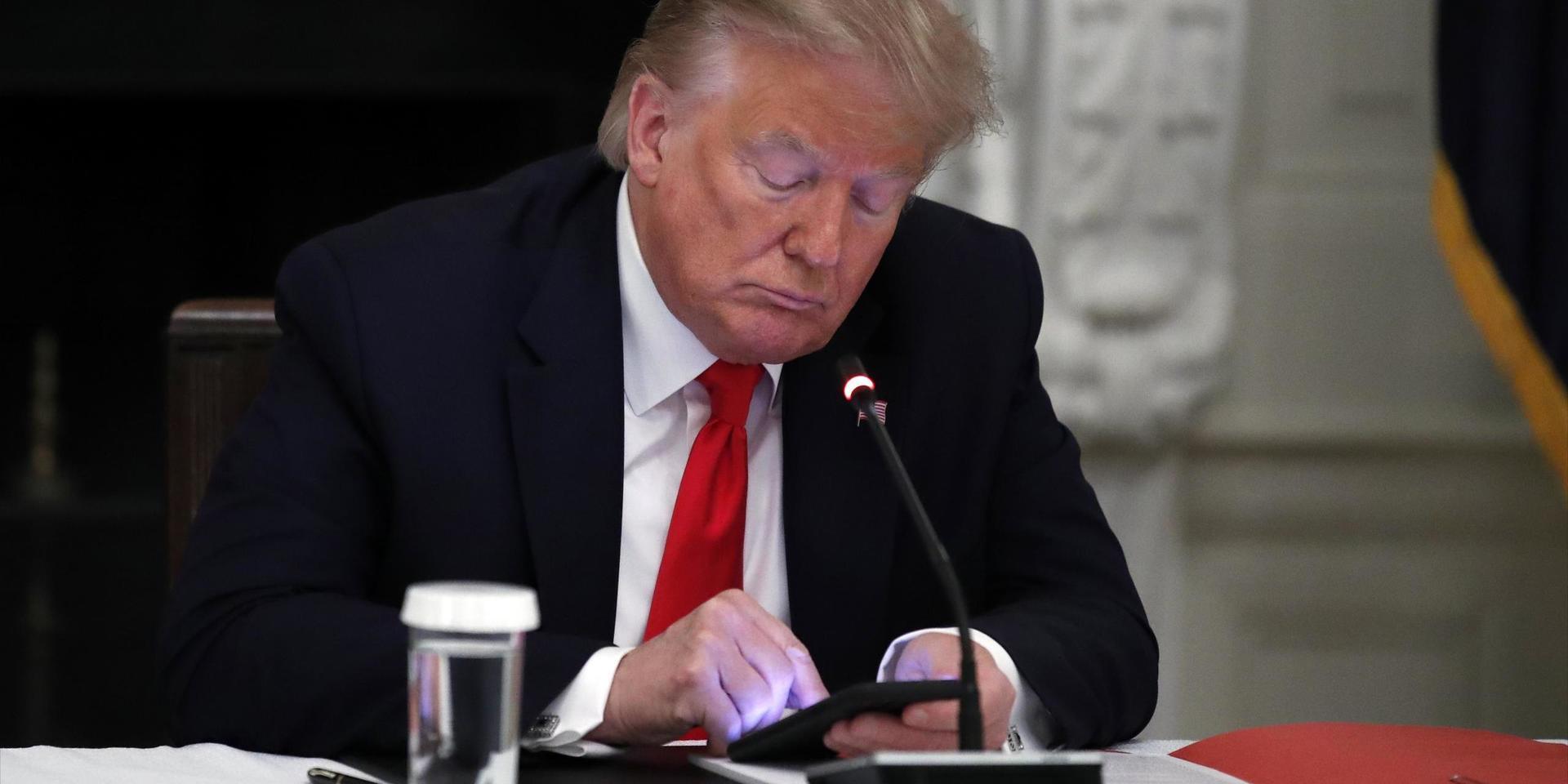 Donald Trump passar på att kolla av telefonen under ett möte. 