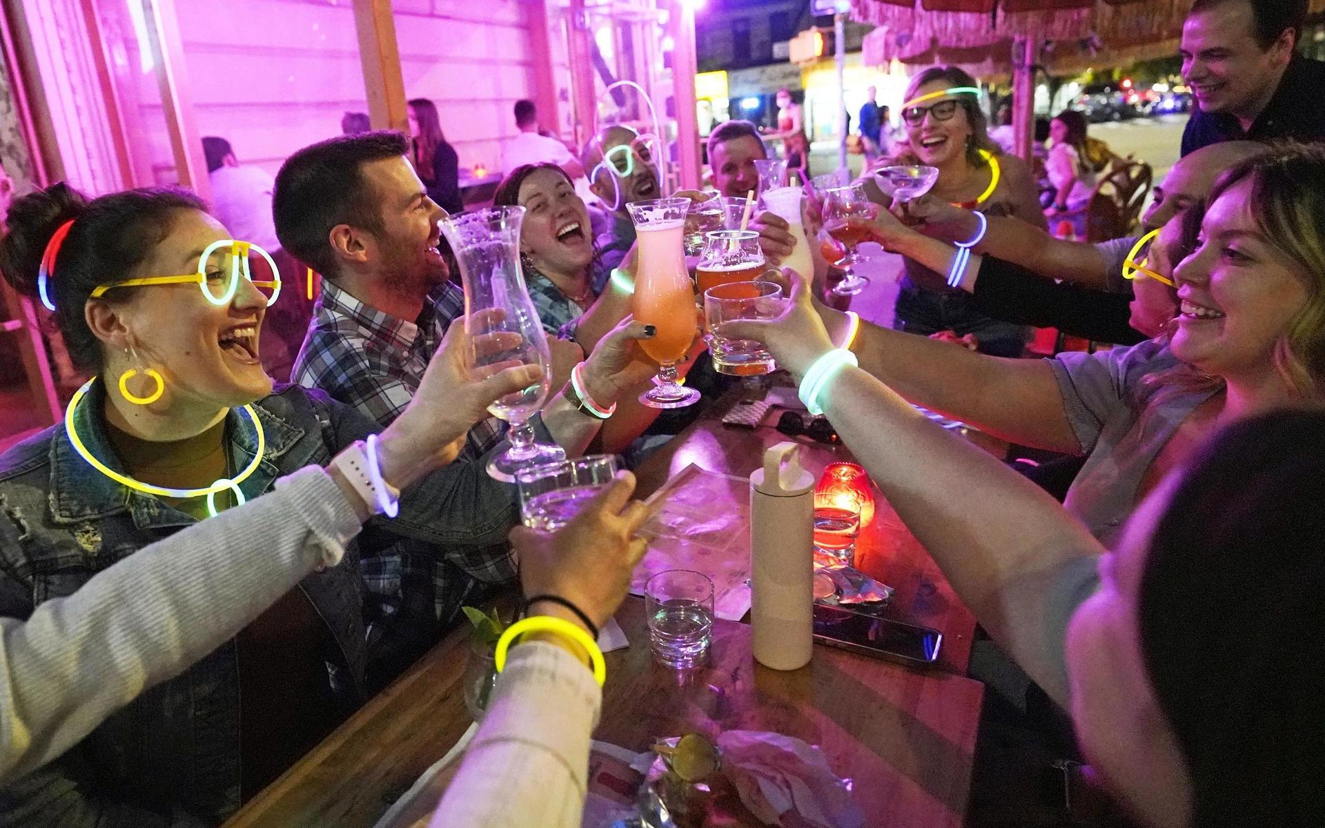 Vänner firar att samhället öppnas upp på en bar på Manhattan.