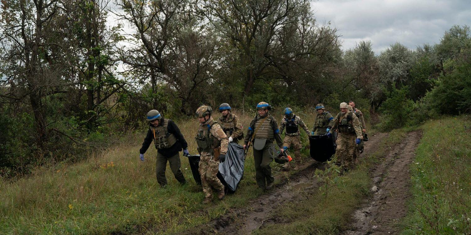 Ukrainska soldater bär undan säckar med kvarlevor av två landsmän, i ett område nära ryska gränsen i Charkiv-regionen. Bilden togs i måndags.