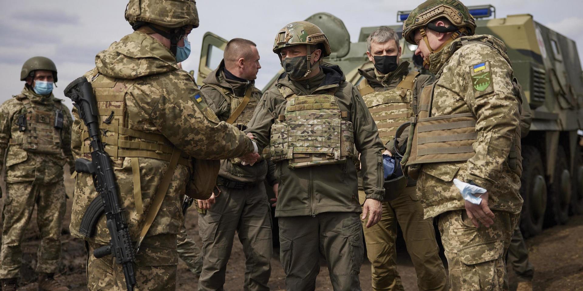 Ukrainas president Volodymyr Zelenskyj (i mitten) besöker landets soldater i östra Ukraina på torsdagen. På andra sidan gränsen mobiliserar Ryssland.