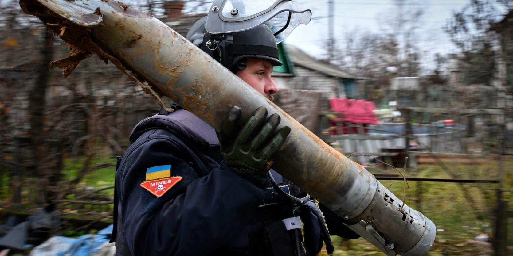 En ukrainsk minröjare bär en del av en projektil under en minröjaroperation i regionen Donetsk den 16 november.