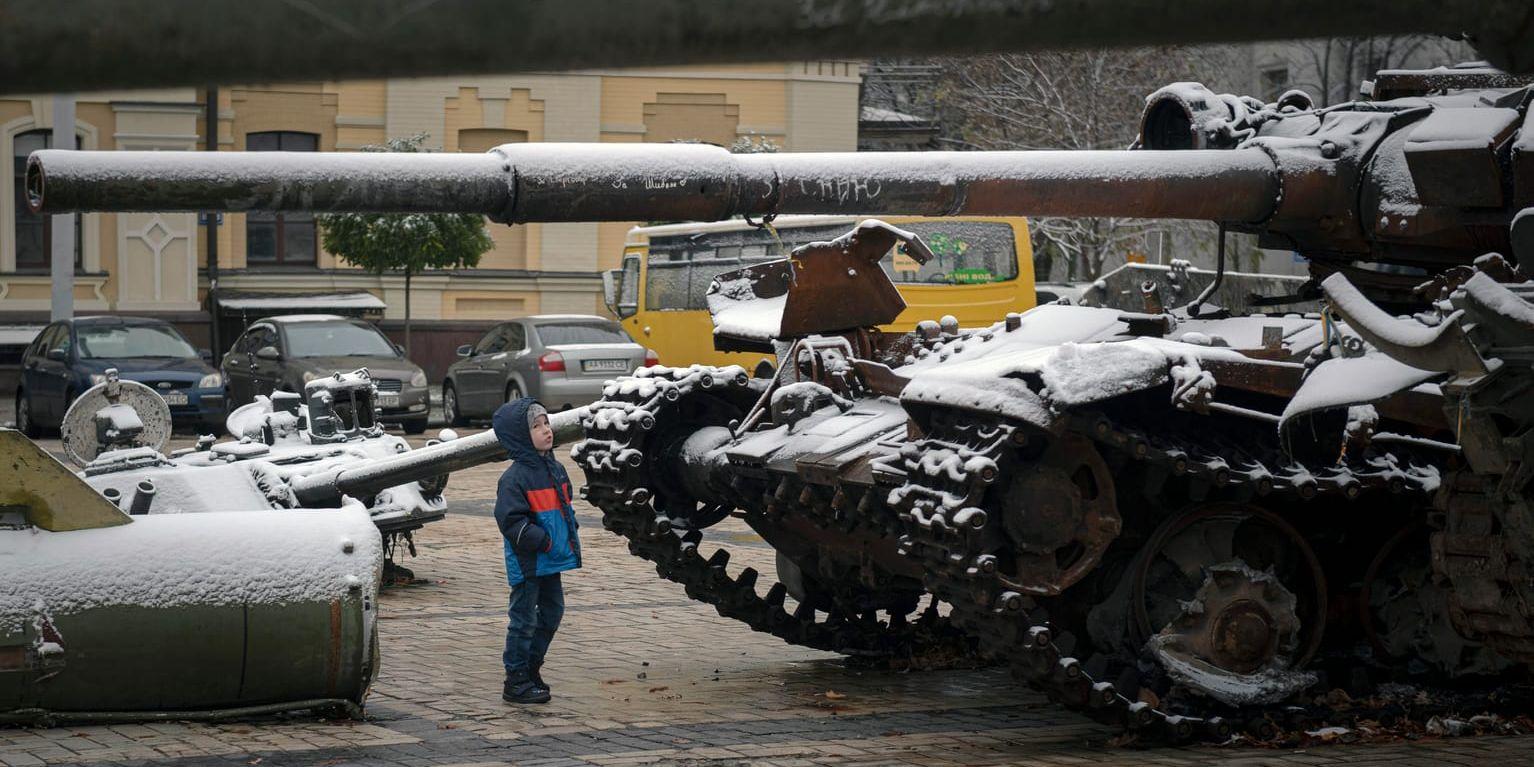 Ett barn tittar på uppställda ryska pansarvagnar – täckta av årets första snö – i centrala Kiev.