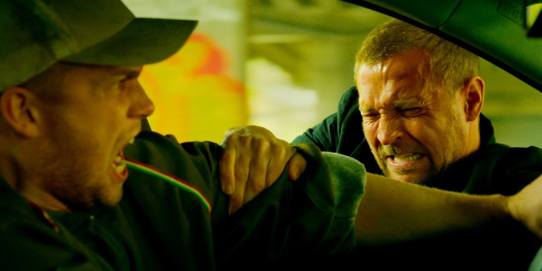 Harry Hole hänger genom bilfönstret för att stoppa buset.