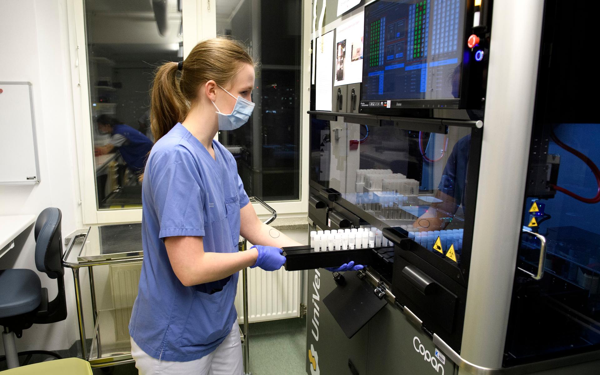 Julia Dahl skjuter in prover i maskinen UniVerse som med sin robotarm suger upp små droppar och komprimerar proverna till mer hanterbar storlek.