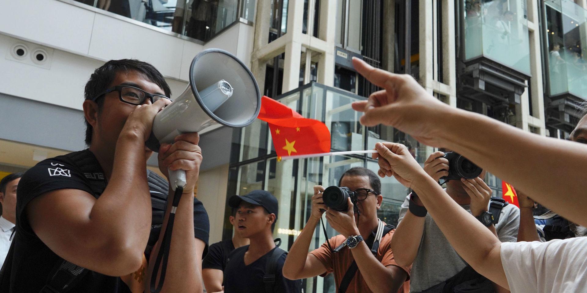 En demonstrant från proteströrelsen försöker göra sin röst hörd framför prokinesiska demonstranter i ett köpcentrum i Hongkong. Bilden togs fredagen den 13 september.