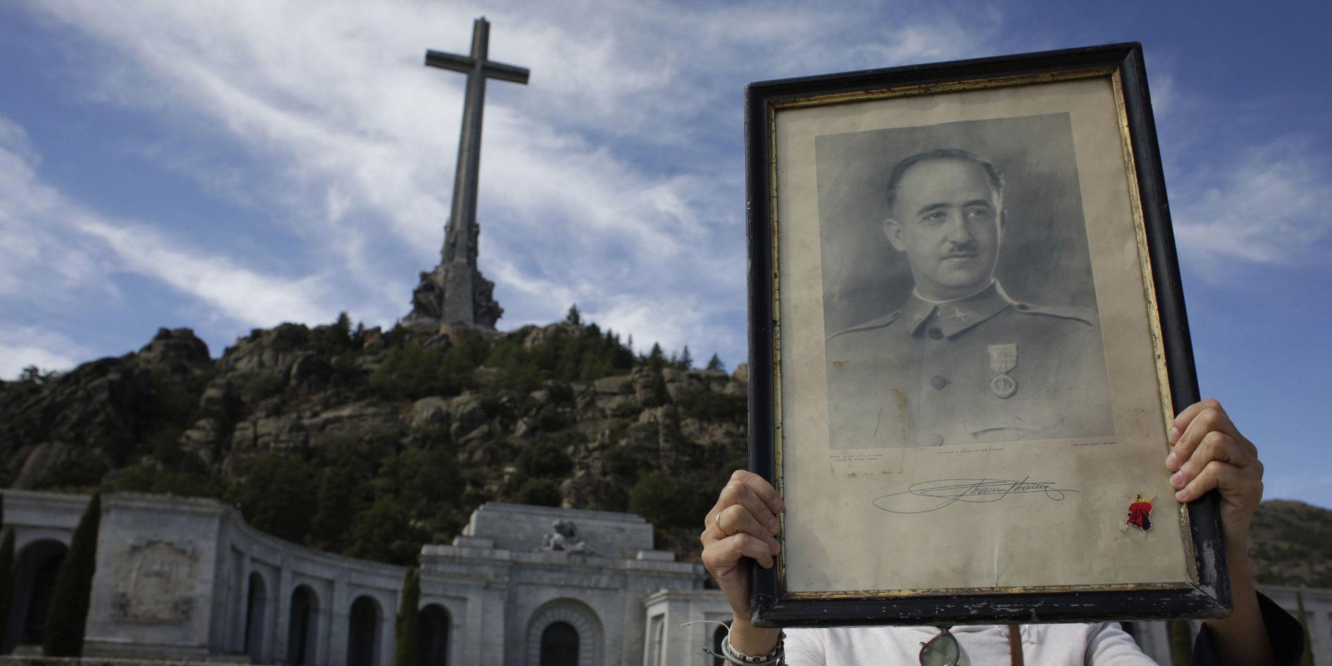 En turist håller upp en tavla föreställande Francisco Franco utanför mausoleet.