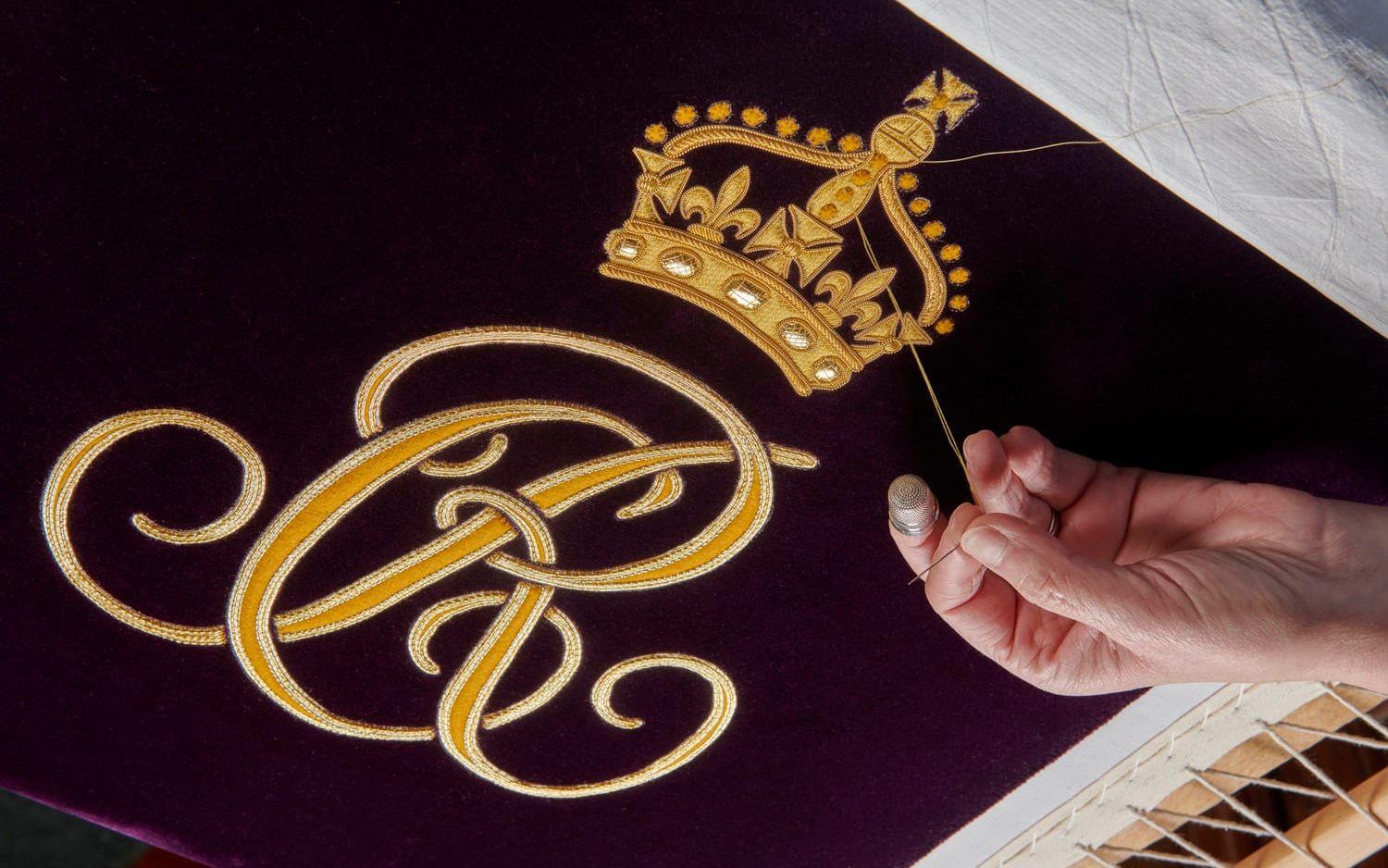 Camillas monogram broderas på ett plagg inför den stundande kröningen.