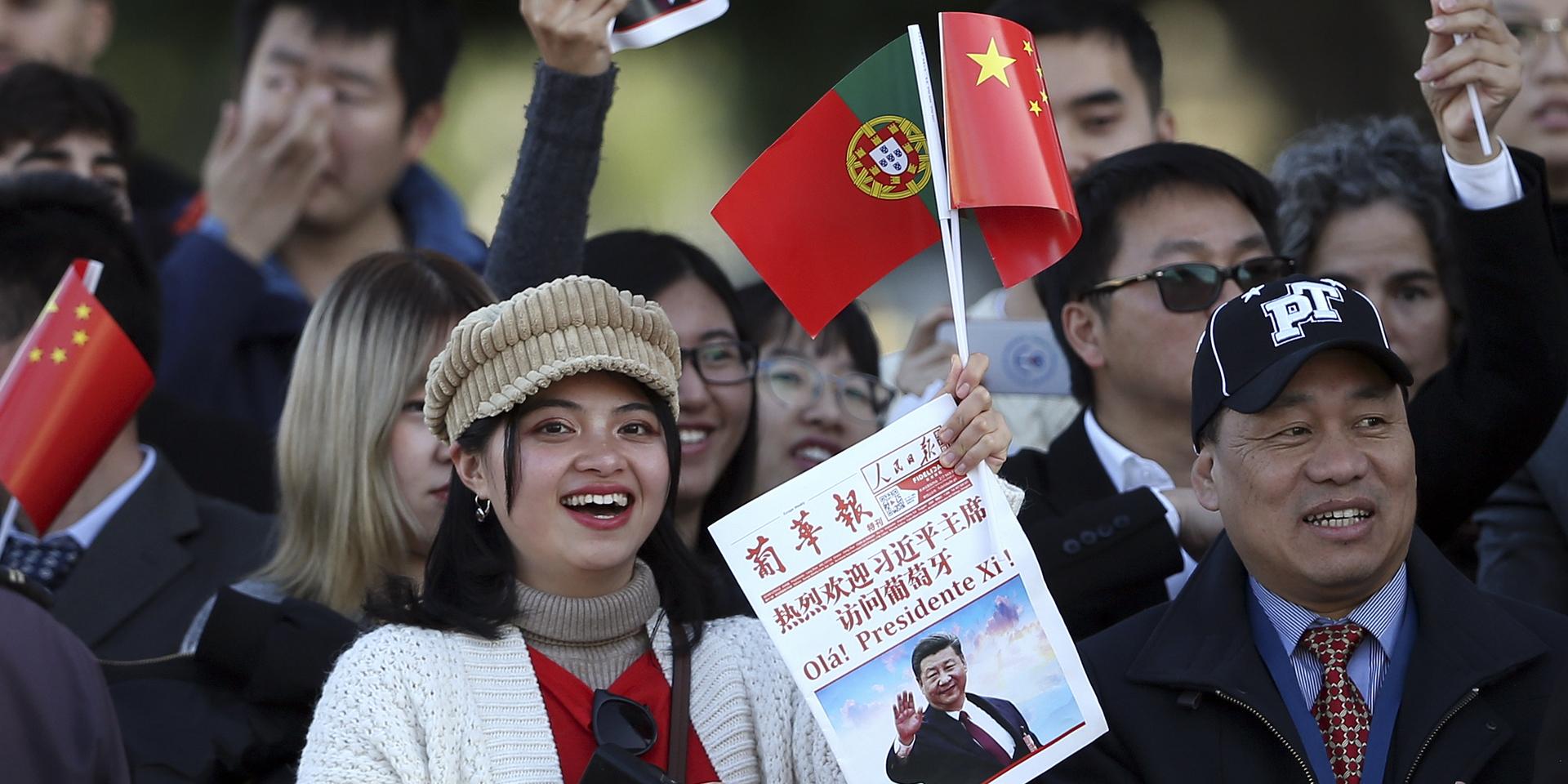 En lyckönskare håller ett foto av Kinas president Xi Jinping och försöker få en skymt honom under en välkomstcermoni för presidenten på statsbesök i Lissabon, 4 december 2018.