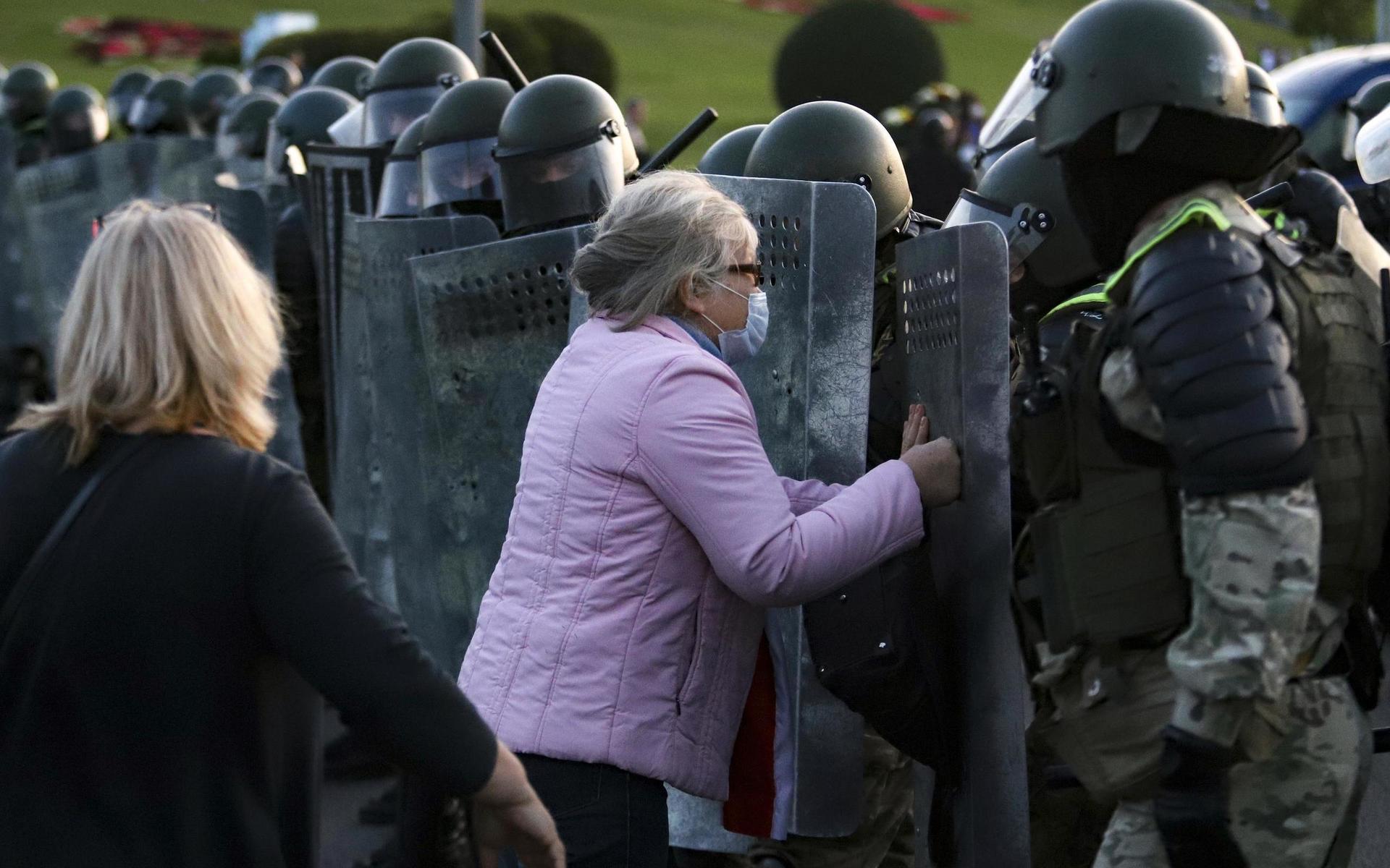En kvinna argumenterar med polisen under en demonstration i Minsk. En fredlig taktik för de protesterande för att stoppa våldet har blivit att försöka avmaskera poliserna, som då avlägsnar sig för att inte bli igenkända.