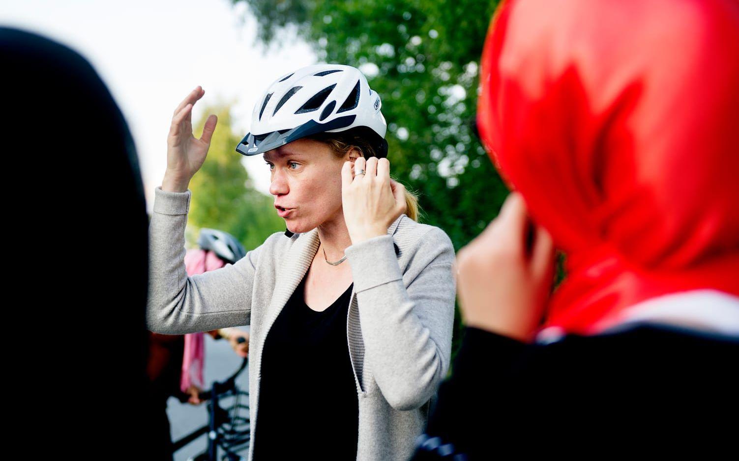 Christina Von Otter, samordnare för språkcafé Möllan demonstrerar hur en cykelhjälm ska sitta.