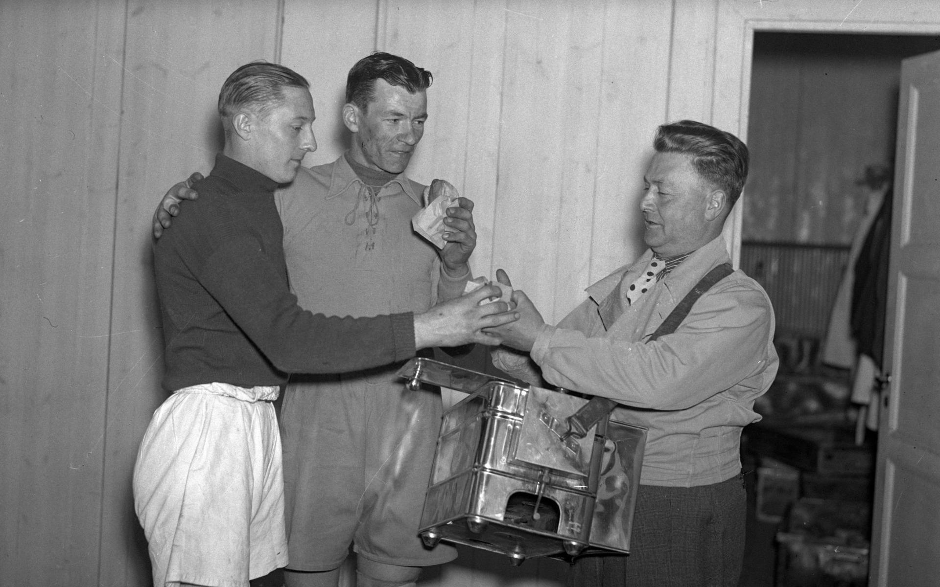 Ullevis matansvarige Giovanni Galligani agerar tillfälligt klassisk korvgubbe med låda på magen när han serverar två fotbollsspelare korv utanför omklädningsrummet den 6 maj 1937. Målvaktens knäskydd antyder att kampen har varit hård.  