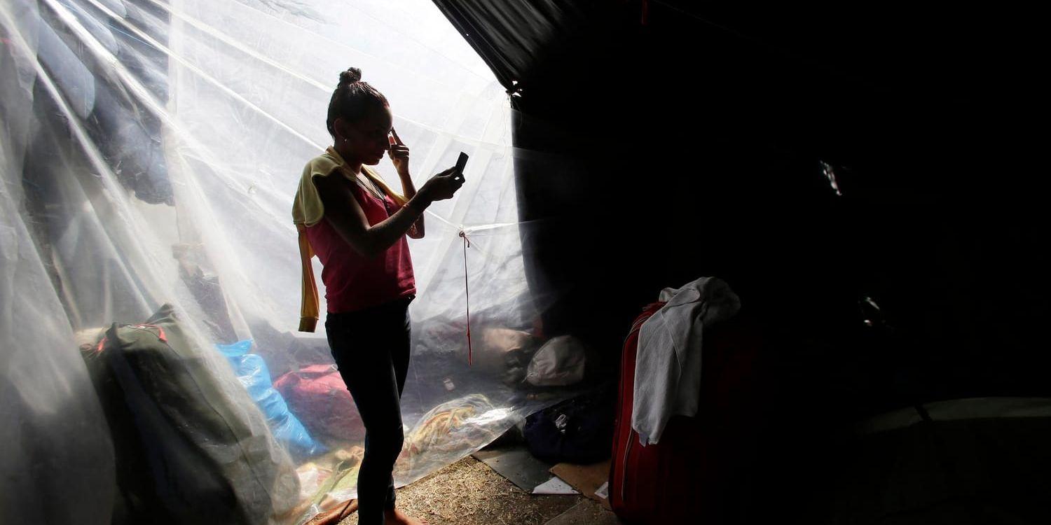 En flykting från Venezuela sminkar sig i ett läger inför arbetsdagen i Ecuadors huvudstad Quito.