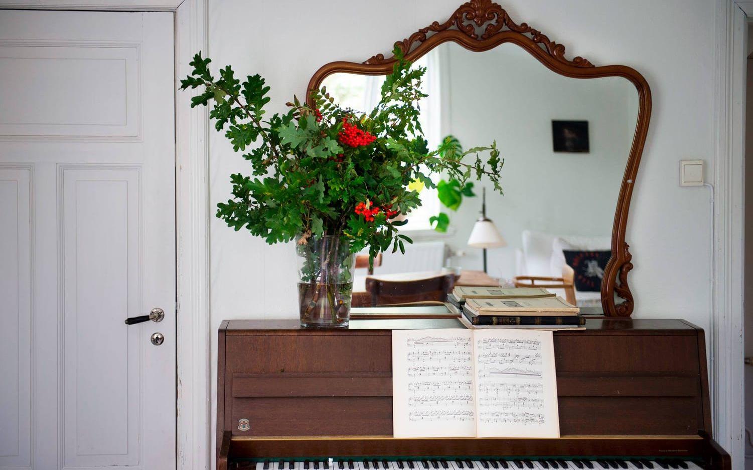 Ovanpå pianot står en spegel som Ida har köpt på auktion samt en stor bukett av kvistar och bär från trädgården – en hållbar bukett.