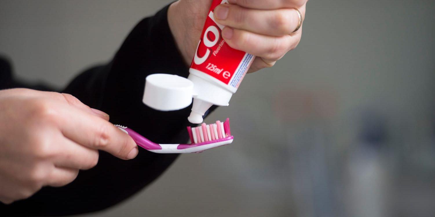 Person som tar tandkräm på sin tandborste.