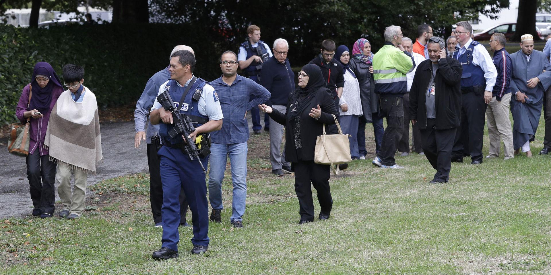 Polis eskorterar iväg personer från platsen för attackerna i Christchurch.