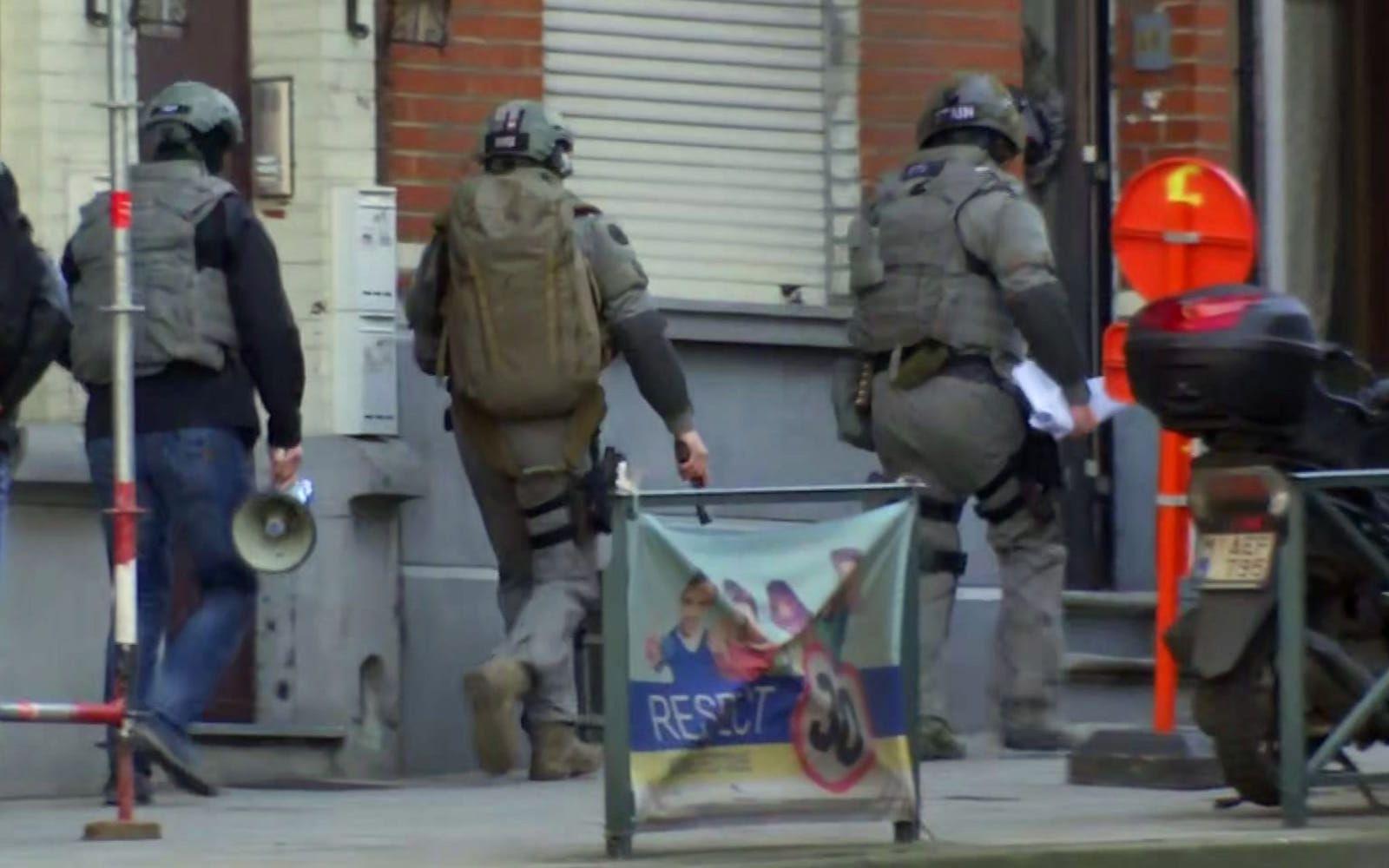 Belgisk insatspersonal tar sig in i en byggnad under den pågående polisinsatsen i Brysselförorten Vorst. FOTO: AP
