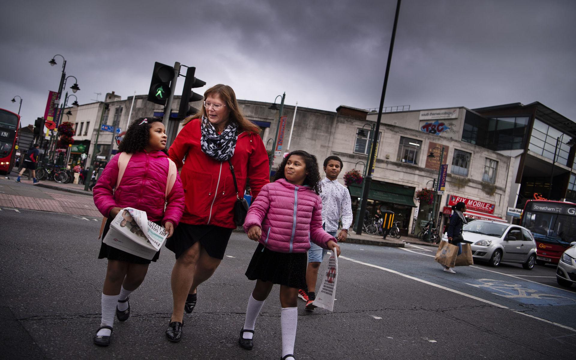 Ulrika Diallo med barnen Isabella, Josephine och Oliver går över gatan i Tooting, i södra London.