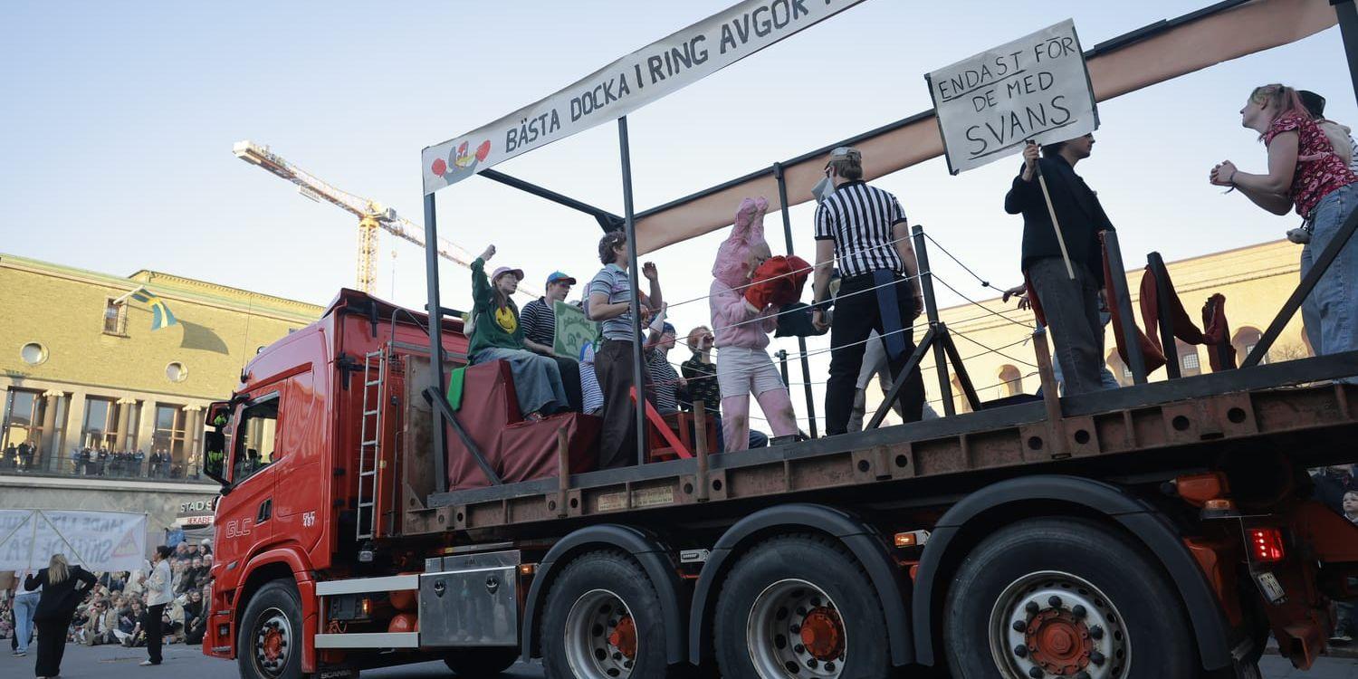 En stor lastbil med massa folk, samt en labubudocka med boxningshandskar
