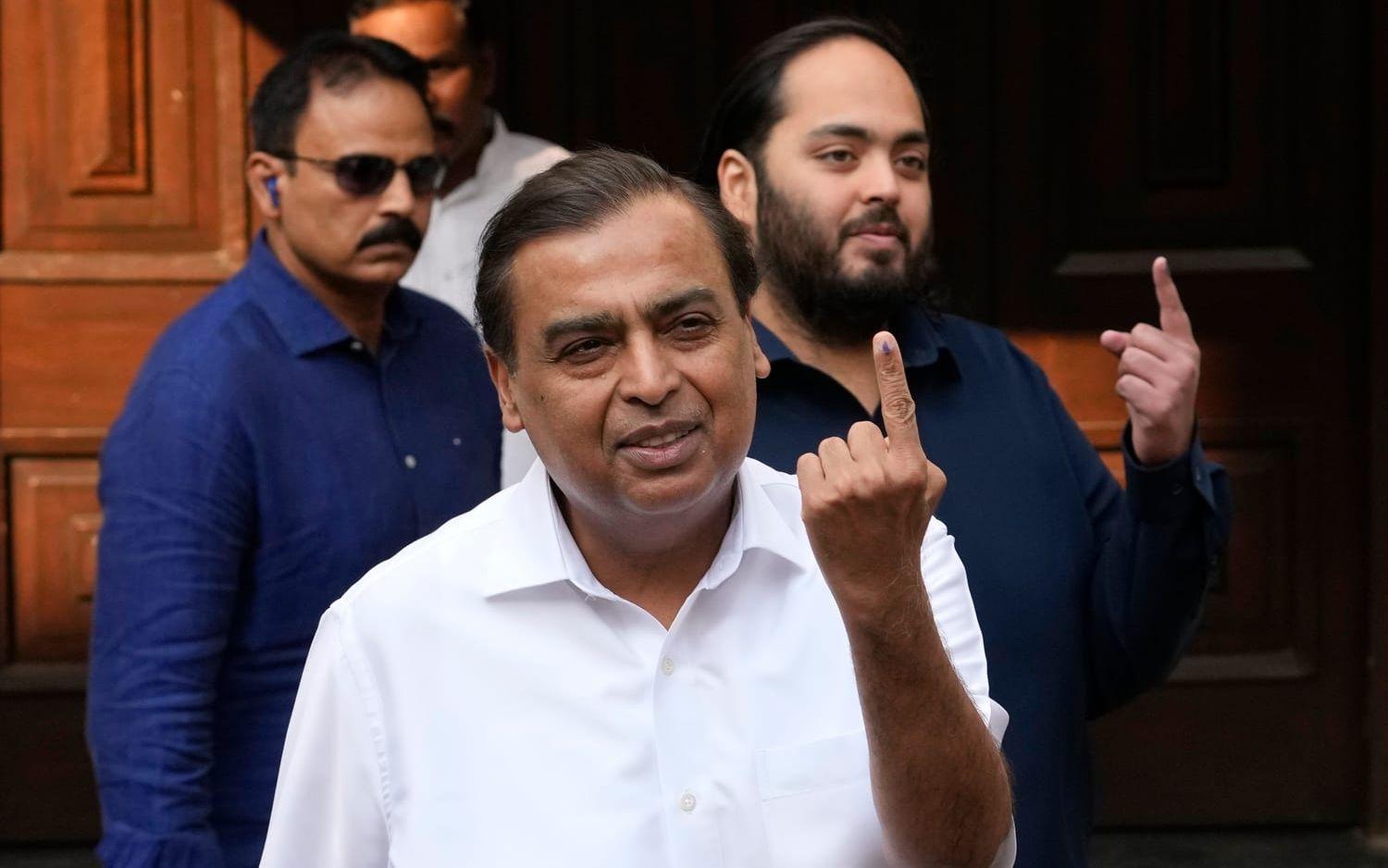 Mukesh och Anant Ambani med fingrar i luften i samband med ett val i Mumbai 2024.