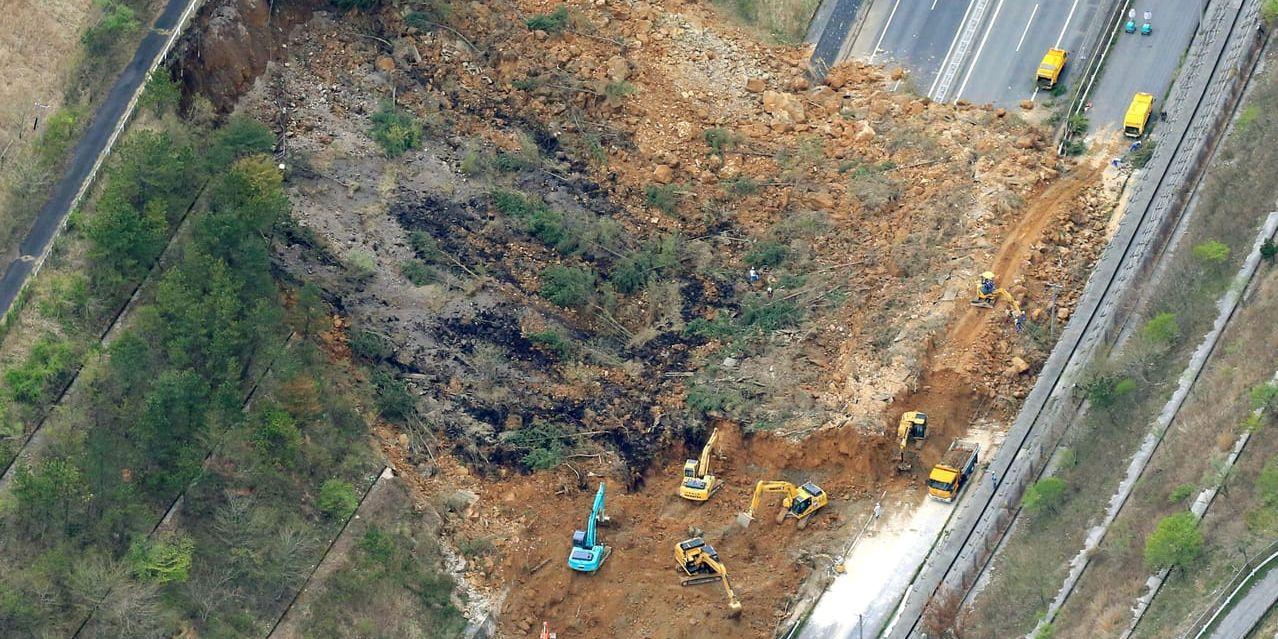 Grävmaskiner försöker röja upp en motorväg som blockerats av ett jordskrev som utlösts av jordbävningen.
