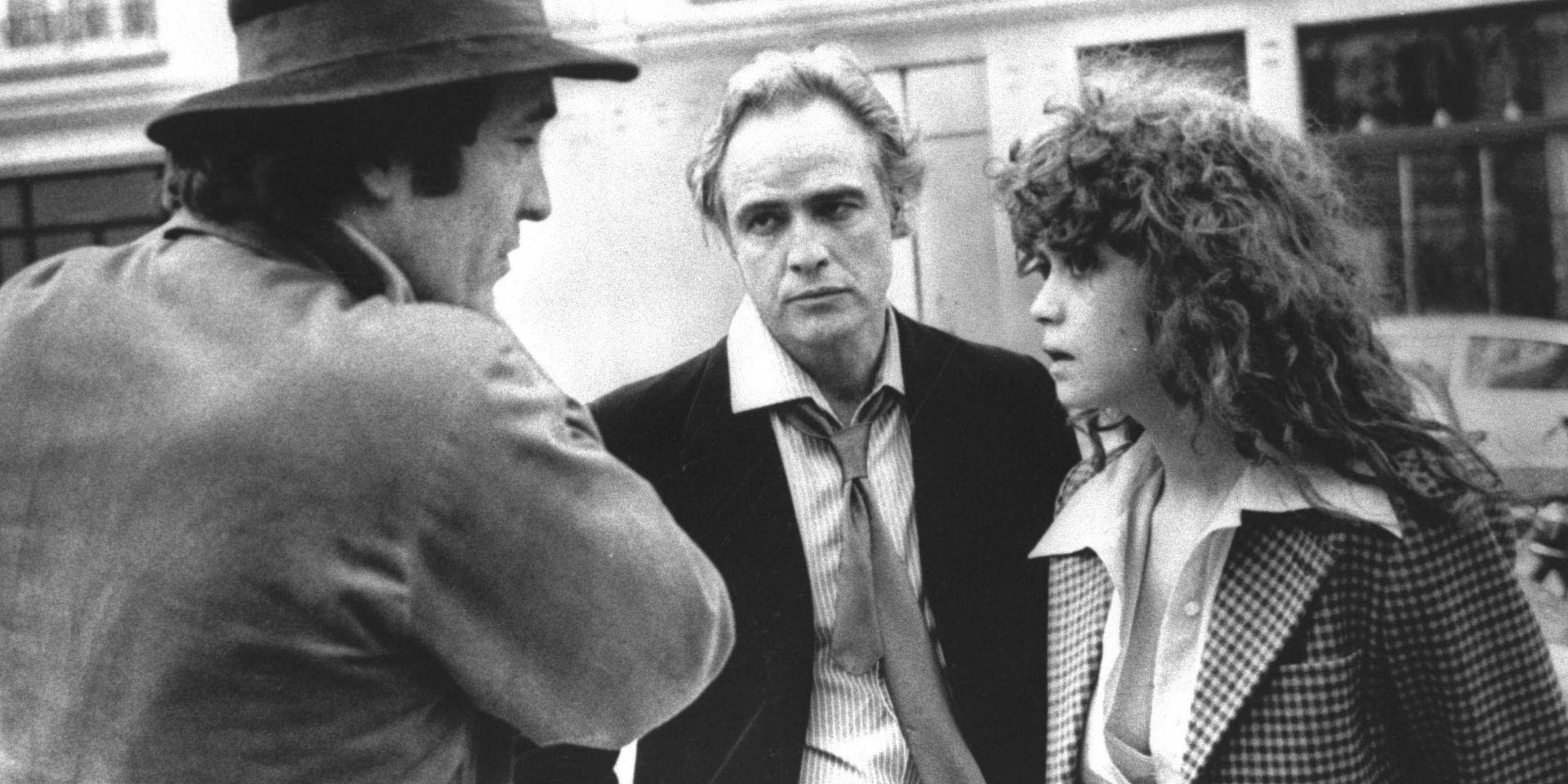 Kontroversiell film. Bernardo Bertolucci (till vänster), diskuterar en scen i Sista tangon i Paris med skådespelarna Marlon Brando och Maria Schneider. Efter inspelningen tog Maria Schneider fullständigt avstånd från regissören på grund av hans metoder.