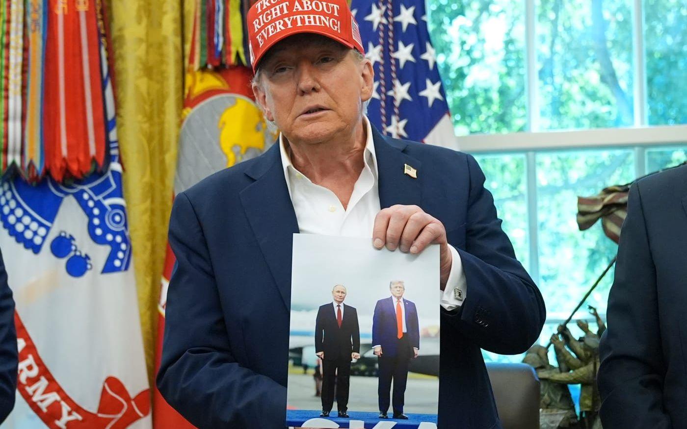 USA:s president Donald Trump håller upp ett fotografi av sig själv och Rysslands dito Vladimir Putin, taget vid ledarnas toppmöte i Alaska i augusti. Arkivbild.