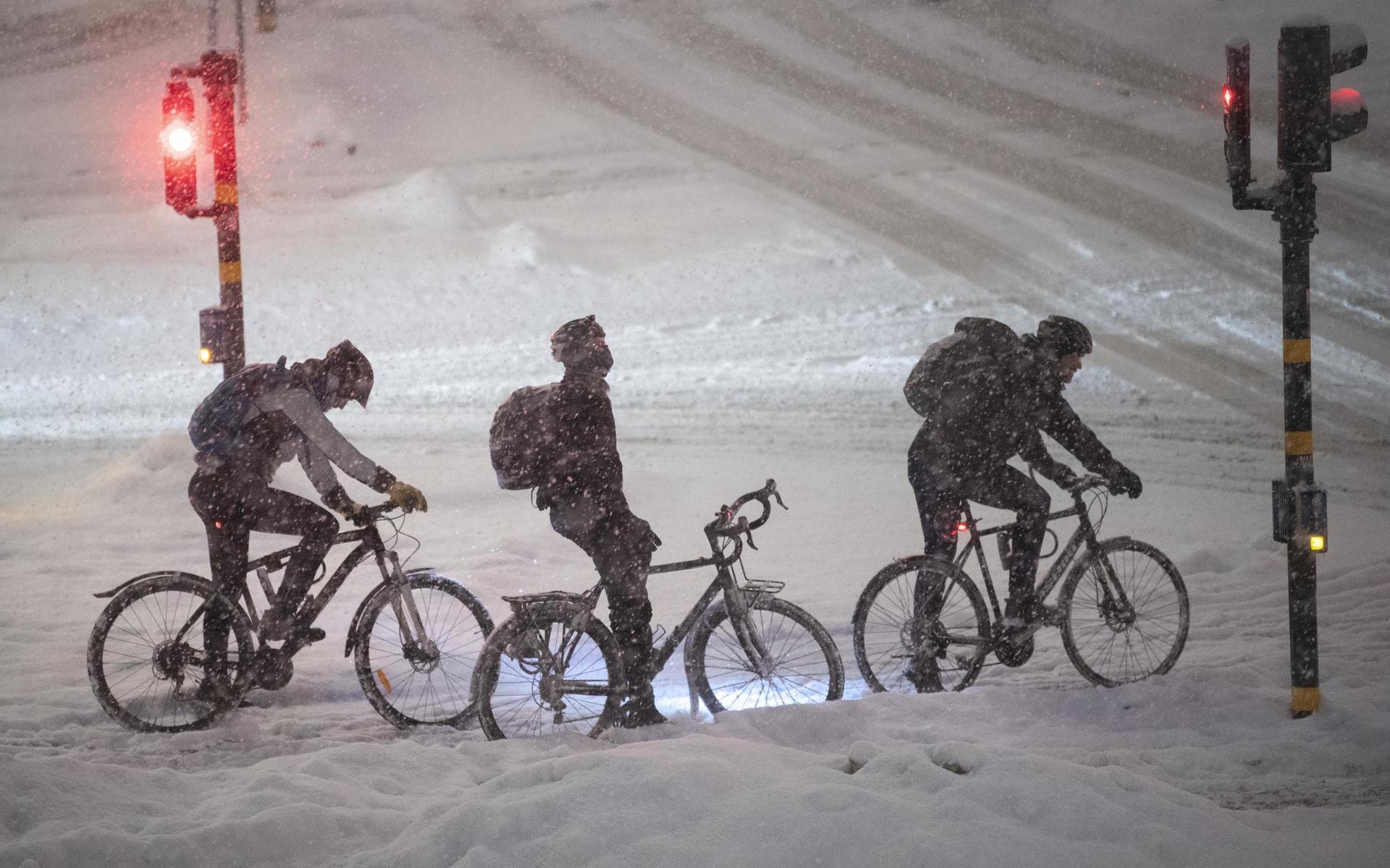 Cyklister vid Tegelbacken i det ymniga snöfallet i Stockholm på tisdagskvällen.