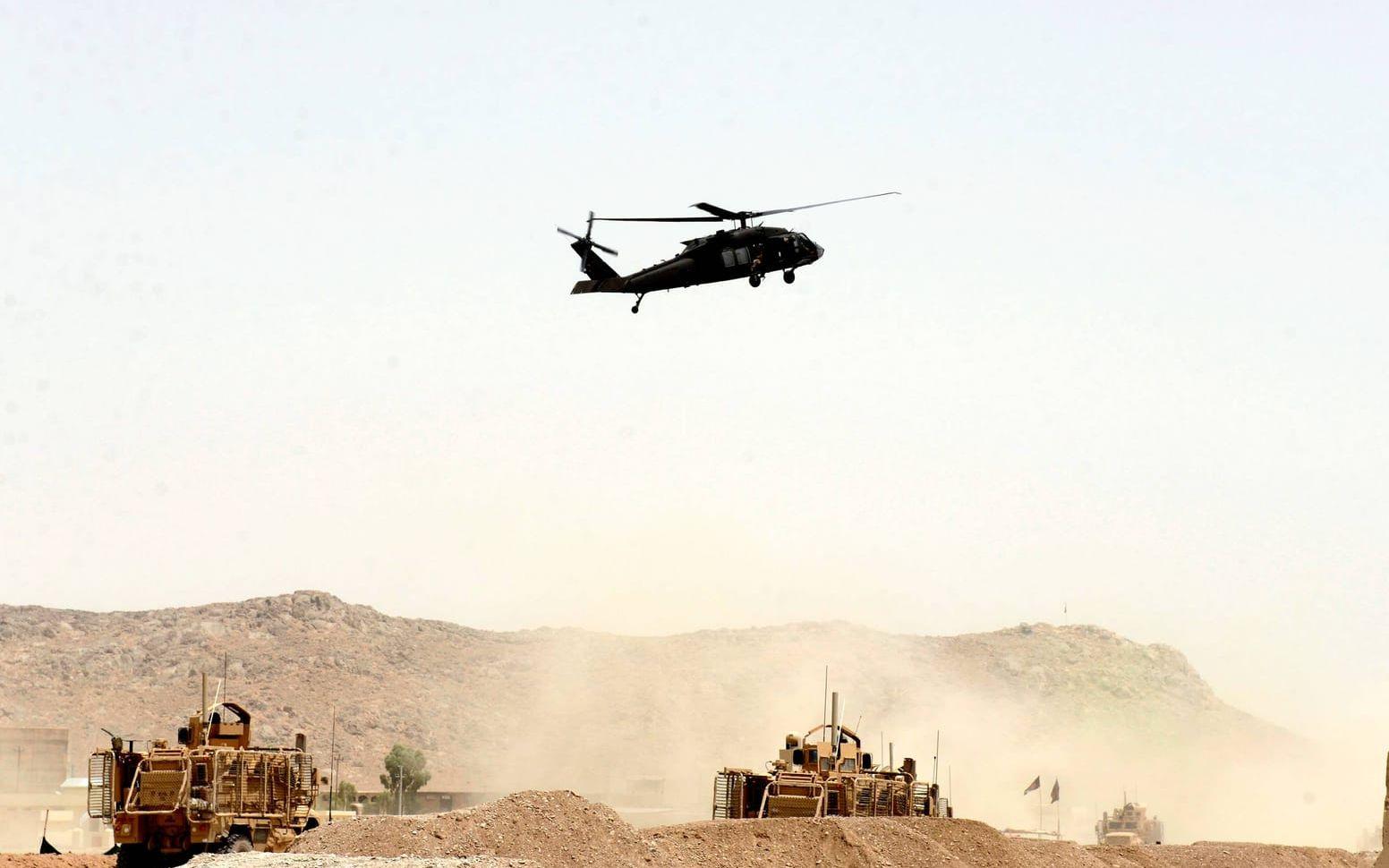 En amerikansk militärhelikopter flyger över platsen där en självmordsbombare slog till mot en NATO-konvoj i Kandahar, söder om Kabul, i början av augusti i år. Bild: AP Photo.
