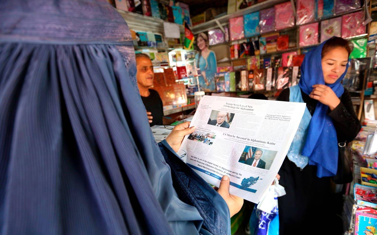 En kvinna läser en lokal dagstidning med en artikel om Donald Trump i Kabul den 22:a augusti i år. Bild: AP Photo/Rahmat Gul.