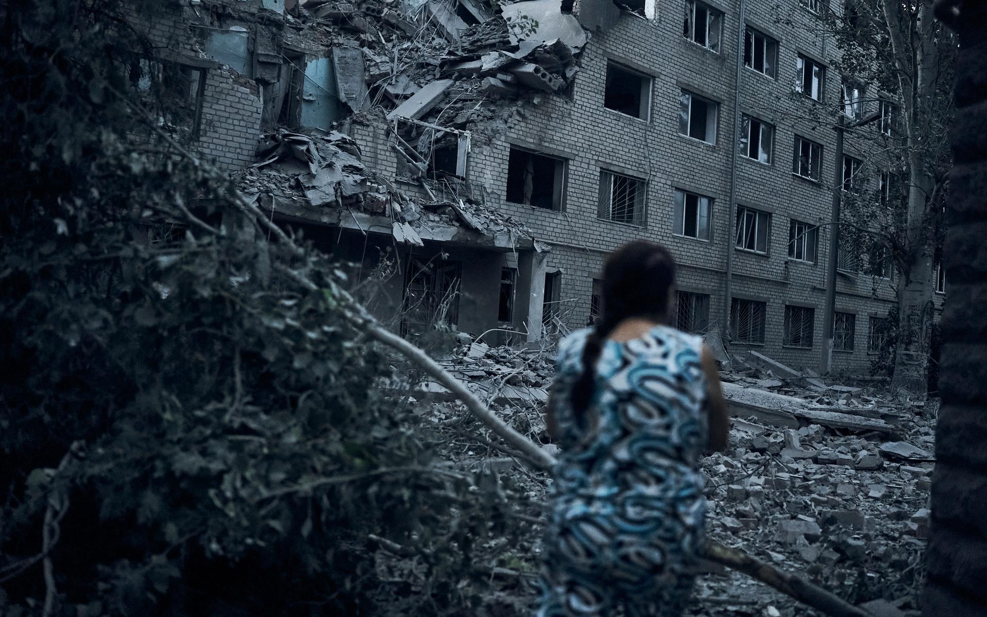 En ukrainsk kvinna promenerar i ett raserat bostadsområde i Mykolaiv.