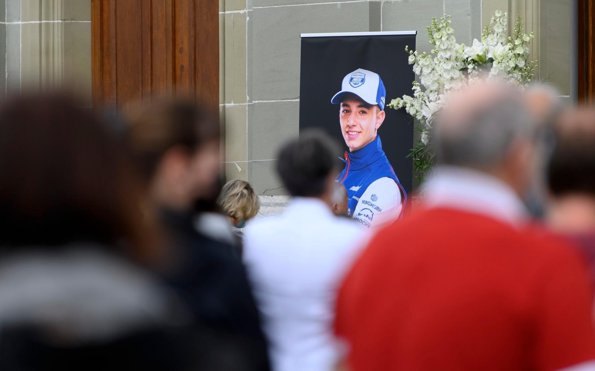 Folk står vid ett porträtt av Jason Dupasiquer vid hans begravning i Schweiz. Föraren avled efter en krasch vid kvalracet i moto3 för den italienska grand prix, den 29 maj 2021.