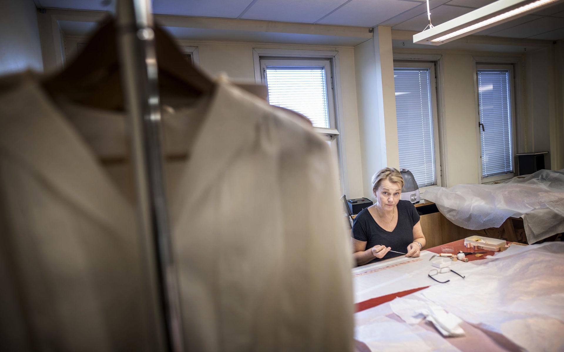 Med stor omsorg restaureras nu en mängd plagg ur museets samlingar inför vårens utställning Göteborgs garderob. Här tittar textilkonservatorn Anne Marie Ryding upp från sitt arbete med en söm.
