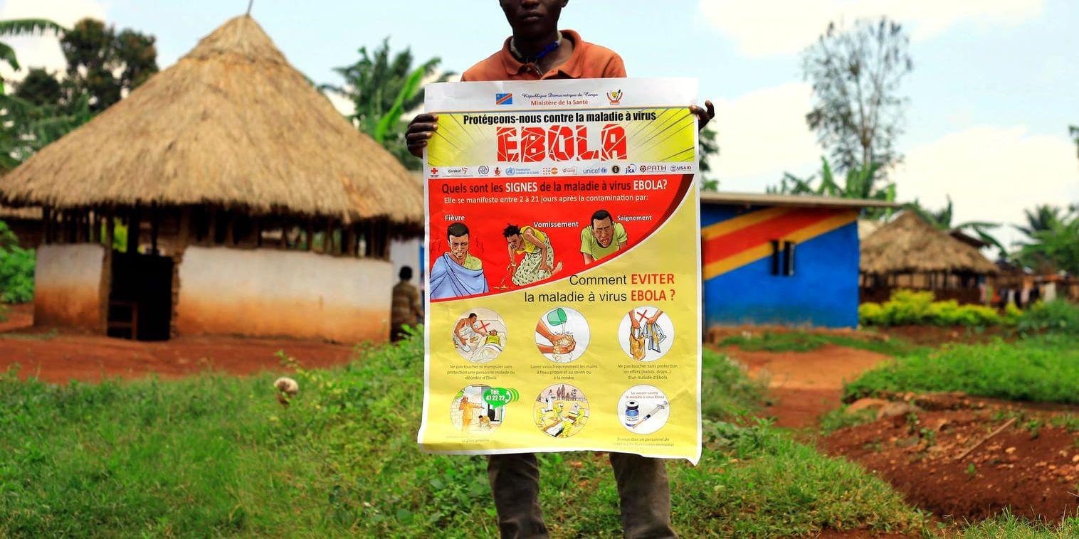 En man i staden Mangina i Kongo-Kinshasa håller upp ett plakat med information om hur man undviker att smittas av ebola.