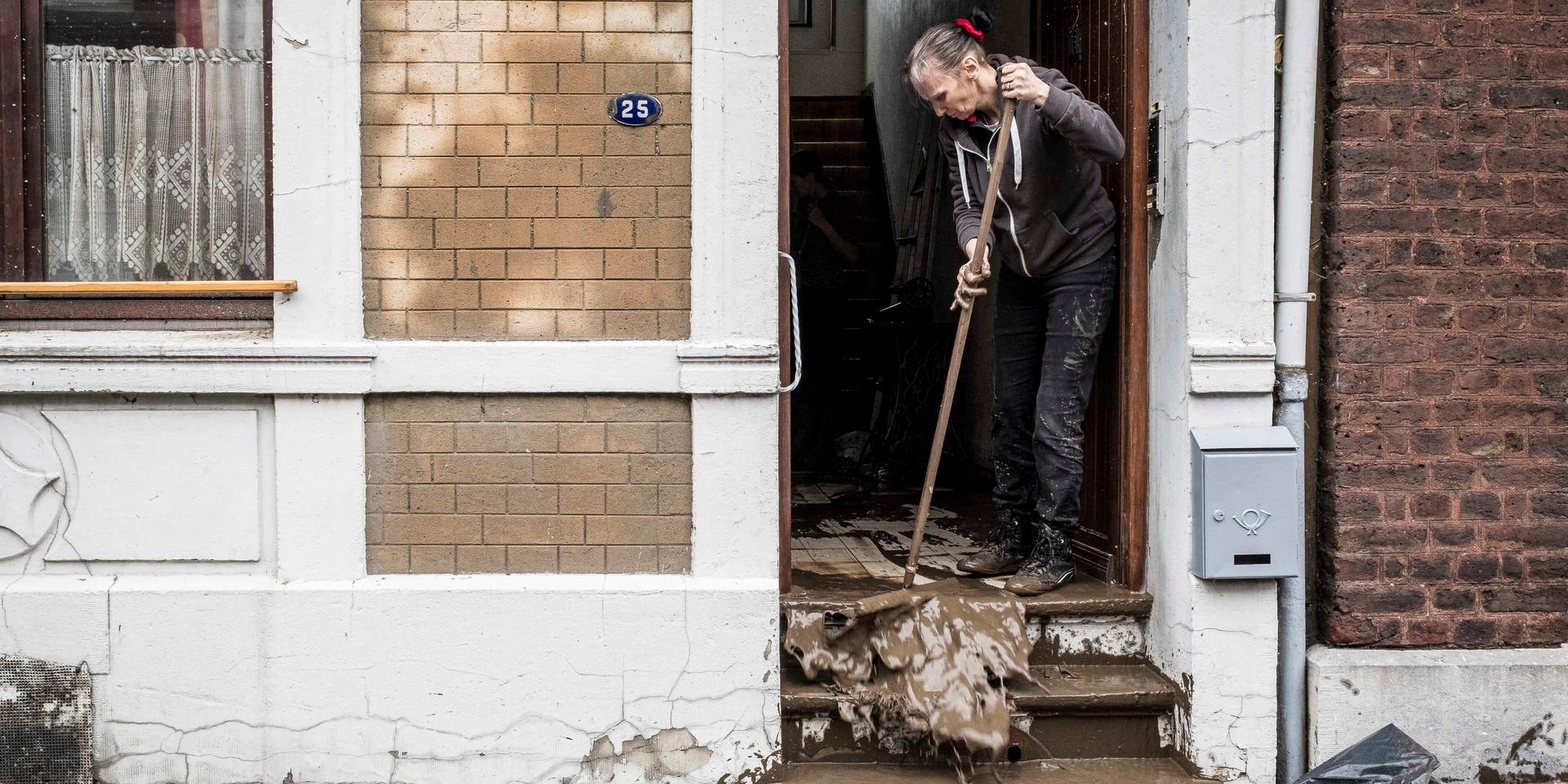 En kvinna städar ut vatten och lera ur sitt hus i Chênée, i Liègeprovinsen i Belgien efter att landet drabbats av kraftiga översvämningar som åsamkat oerhörda skador och krävt många människoliv.