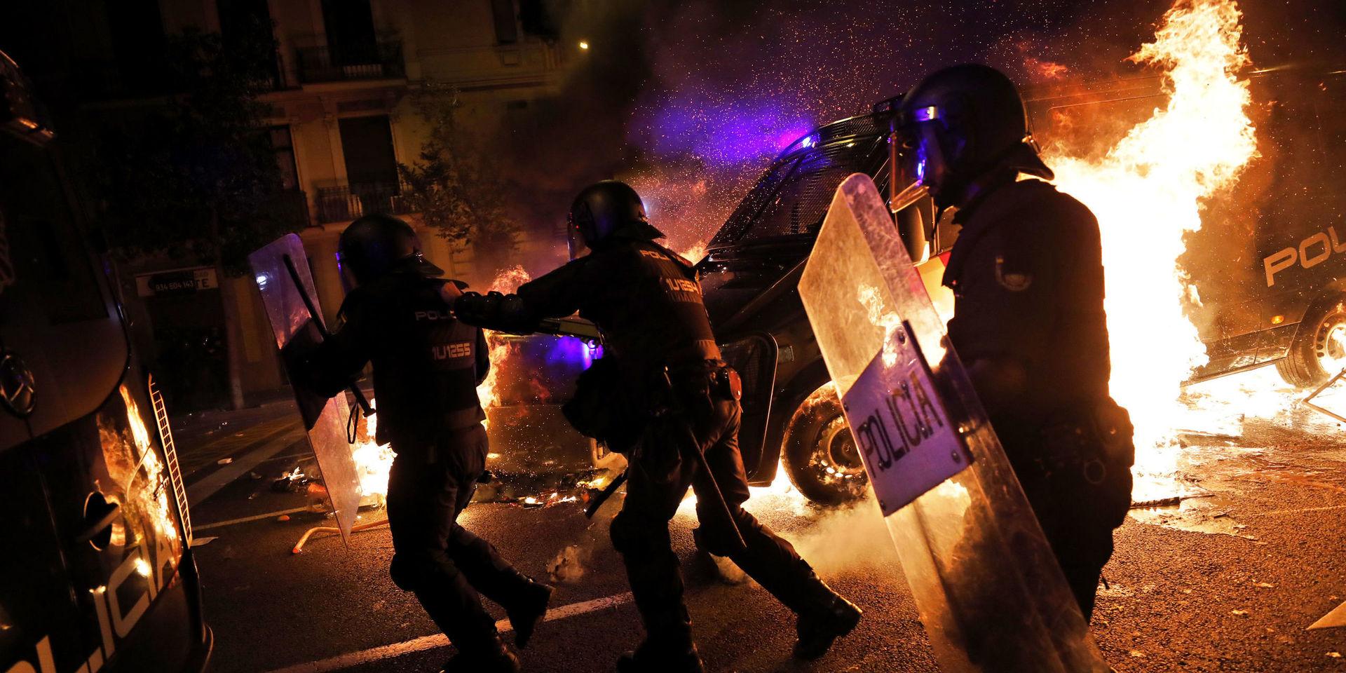 Poliser springer undan när en polisbuss fattar eld vid protesterna i Barcelona.