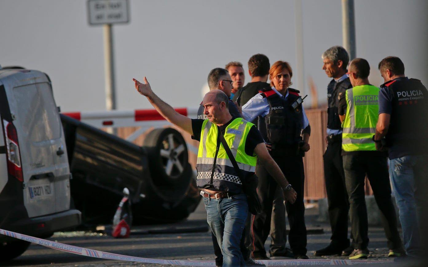 Poliser vid en voltad bil på strandpromenaden i Cambrils där fem terrorister gick till attack under natten till fredagen. Alla fem sköts till döds. FOTO: AP
