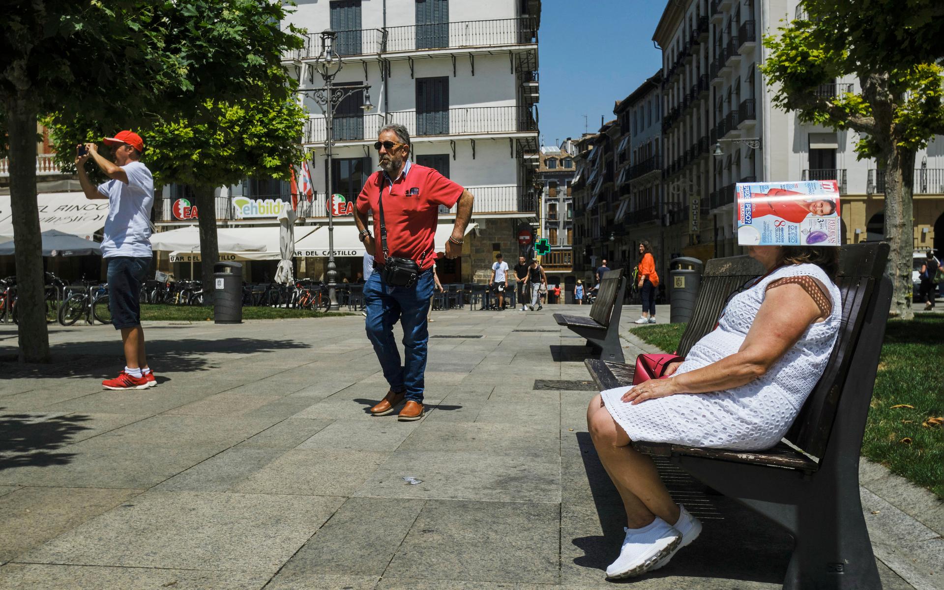 I Pamplona har en kvinna lagt ett magasin över huvudet som skydd för den heta solen.