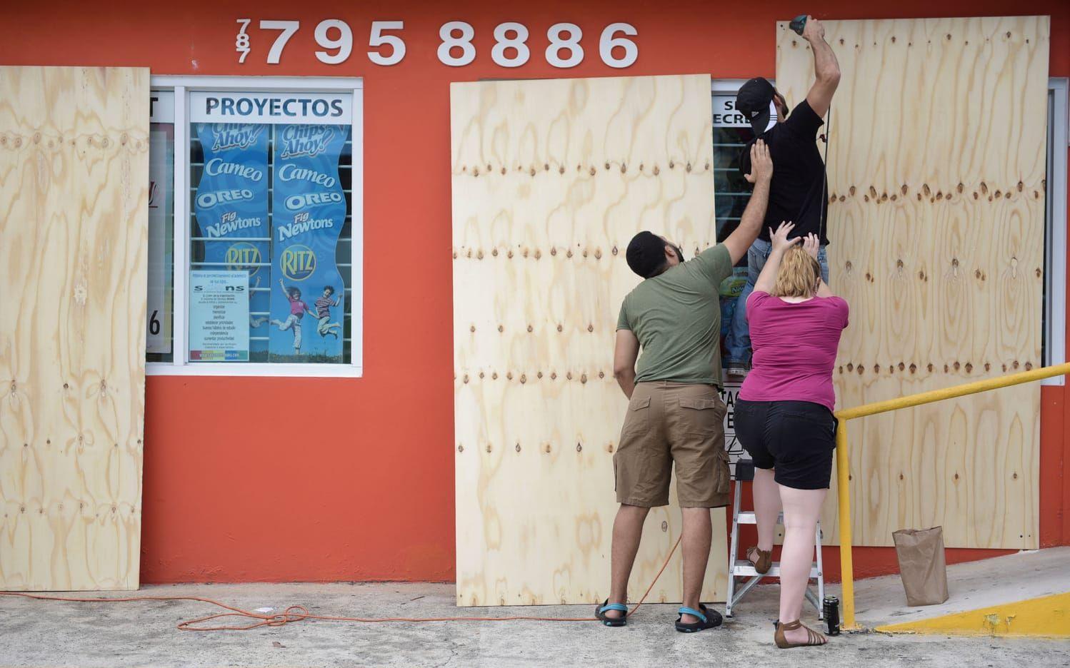 Christopher Rodriguez får hjälp när han täcker över fönster till en matbutik i Puerto Rico. Bild:Carlos Giusti
