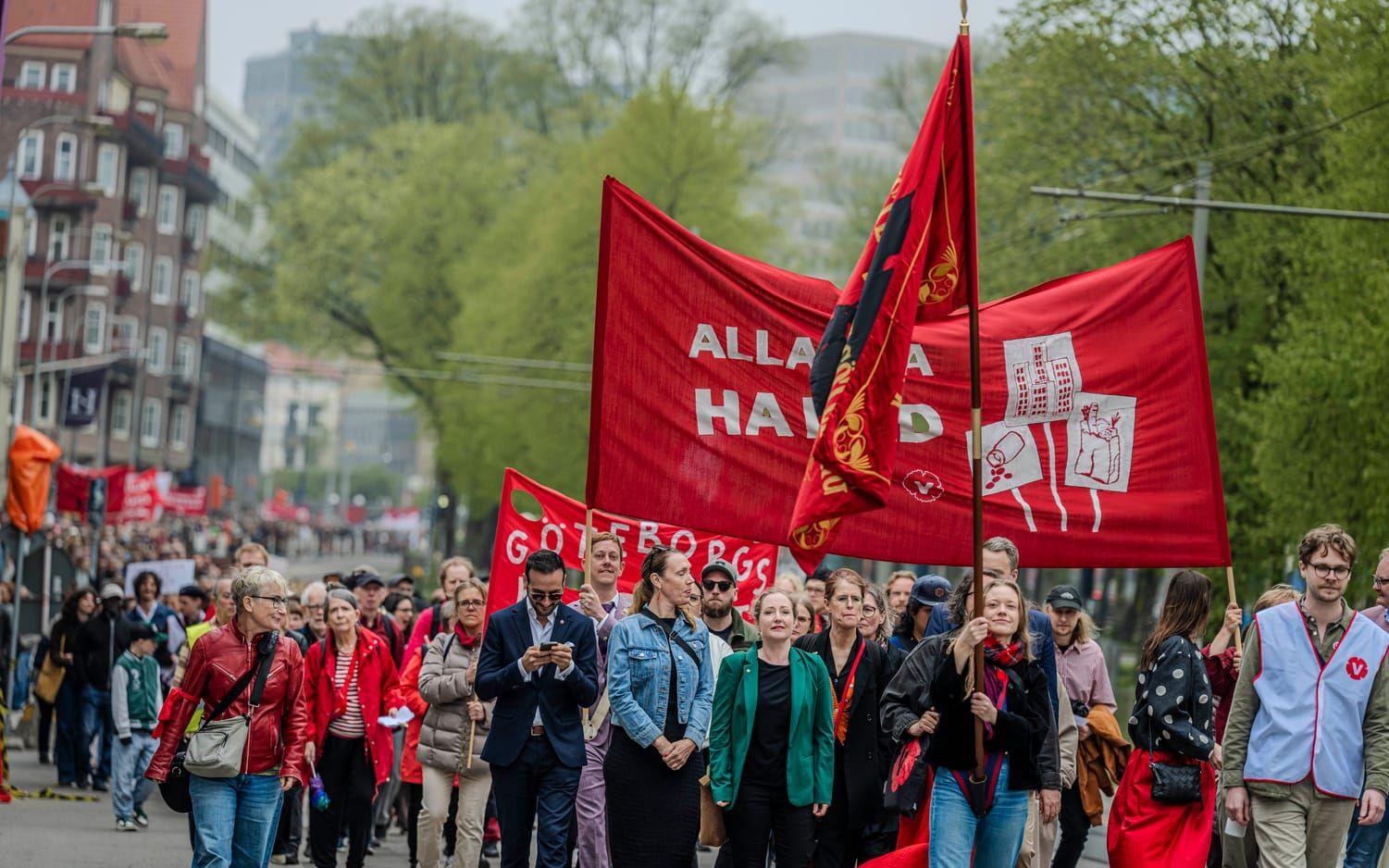 Personer tågar med röda flaggor och banderoller under ett första maj-tåg i Göteborg.