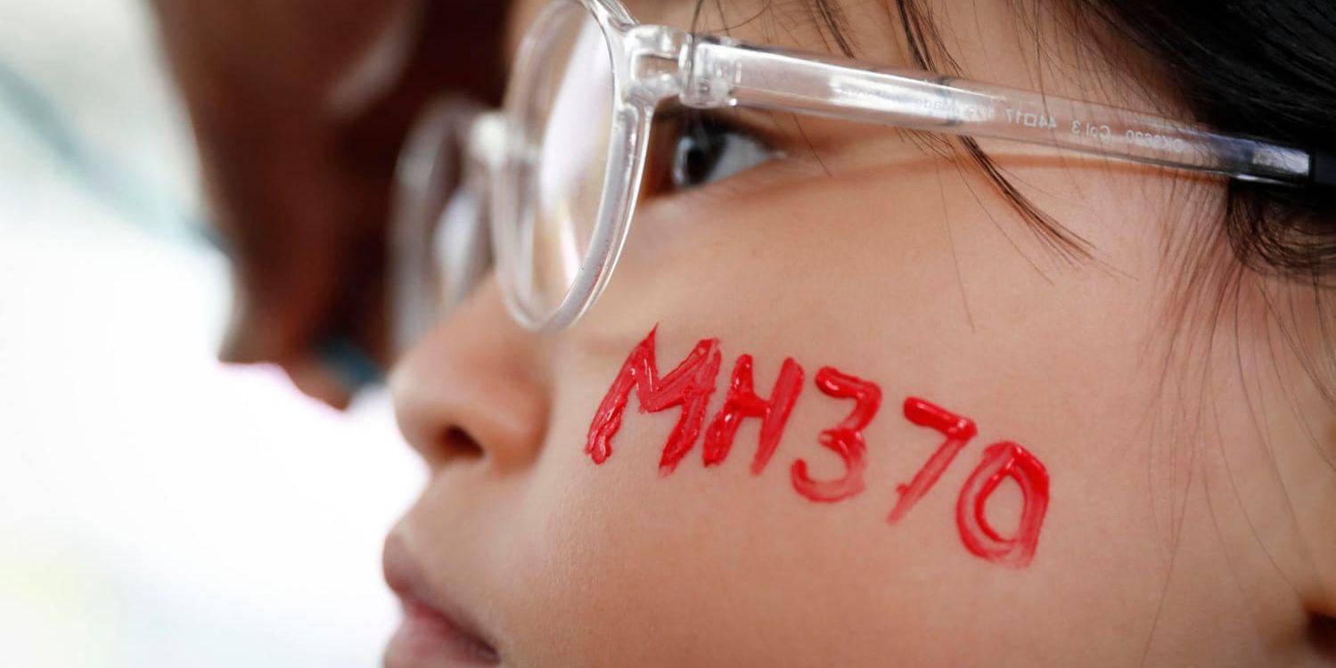 En liten flicka har målat namnet på det försvunna Malaysia Airlines flight MH370 på kinden under en minnesstund i Kuala Lumpur, fyra år efter att planet försvann. Arkivbild.