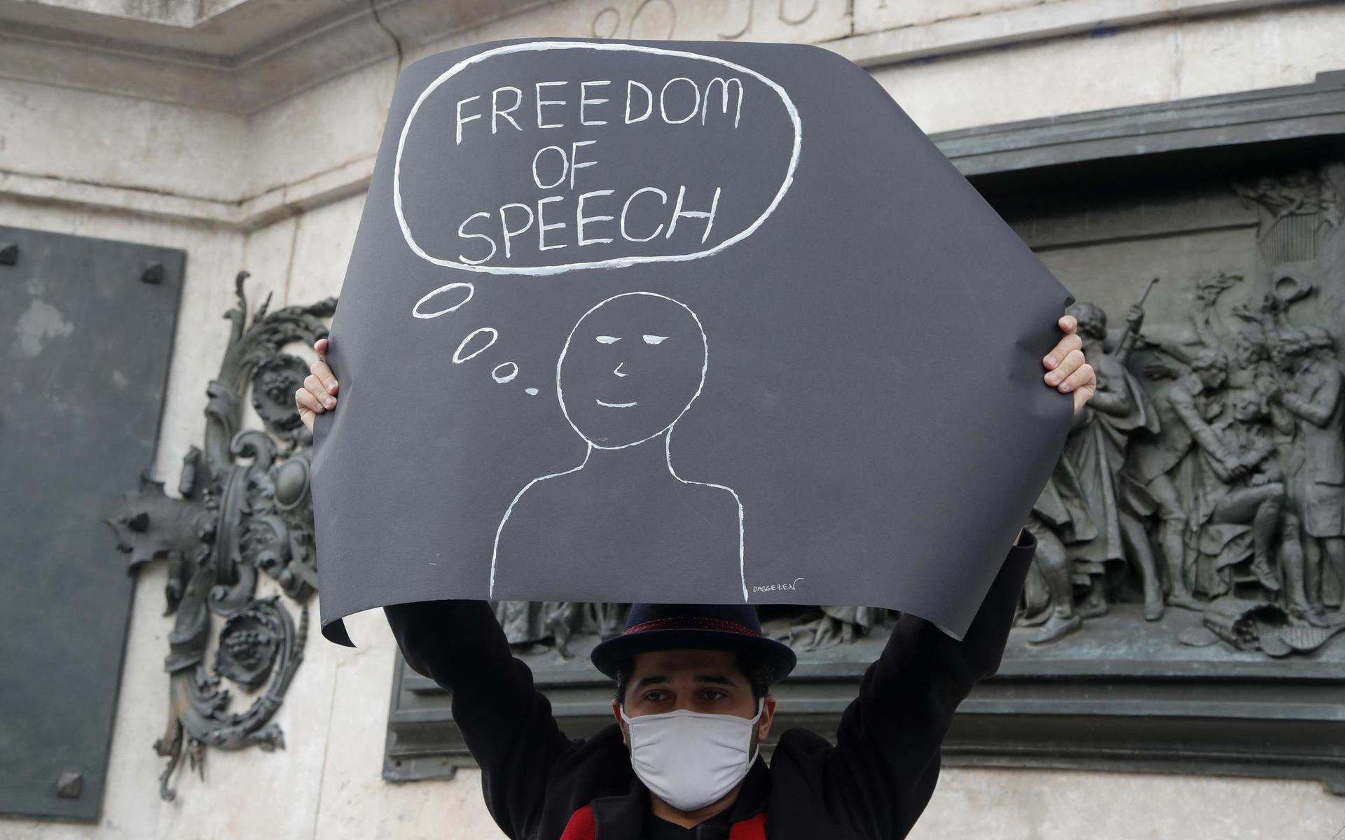 En demonstrant med en skylt som läser ”Yttrandefrihet” under demonstrationen.
